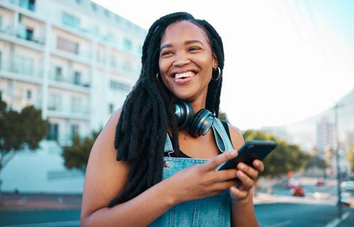 A college age, smiling woman using her smartphone