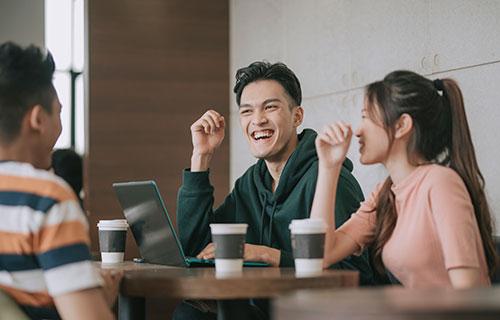 A group of students use their devices in a coffee shop