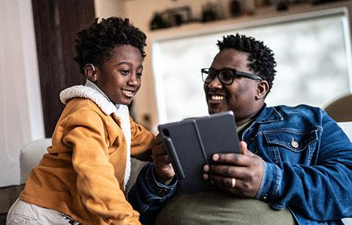 A father and son bond with each other over a tablet.