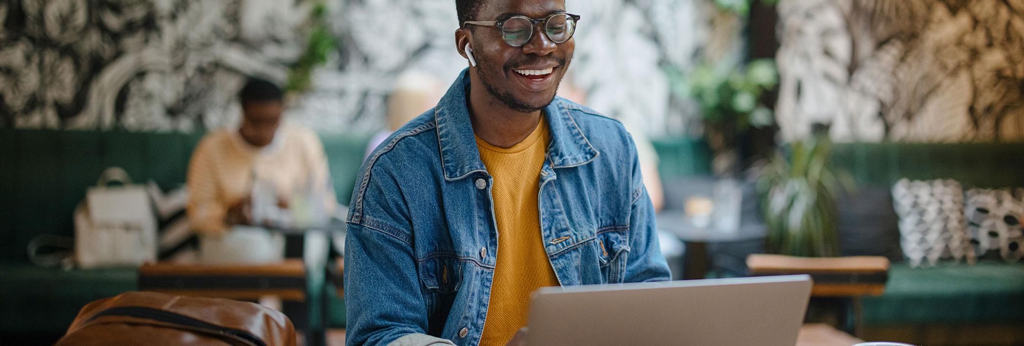 A young man uses a laptop in a coffee shop